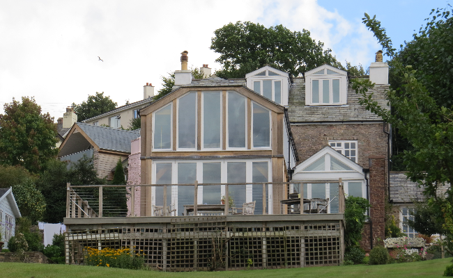 A wooden beam house with large windows in front.